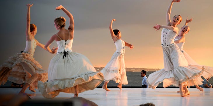 Cinco bailarinas bailando en el escenario con ropa de danza.