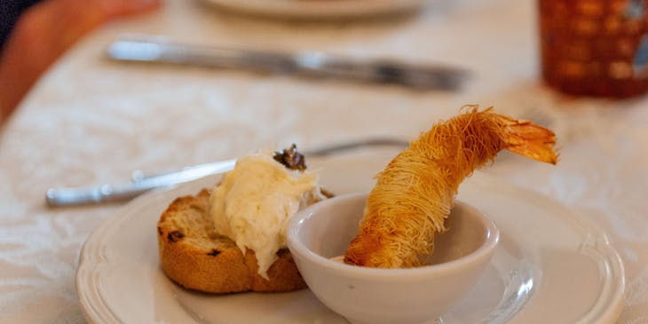 Crostino con baccalà mantecato e un gambero fritto in un piatto in un ristorante veneto.