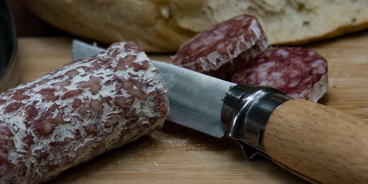 Un salame tagliato a fette sopra un tagliere dentro una norcineria.