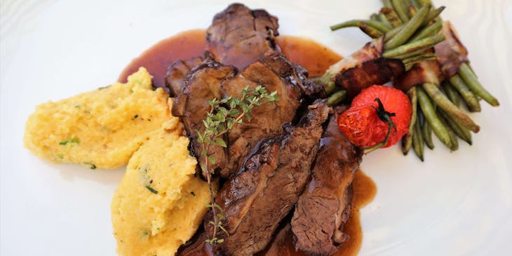 Polenta e brasato di carne serviti su un piatto bianco in un ristorante valdostano.