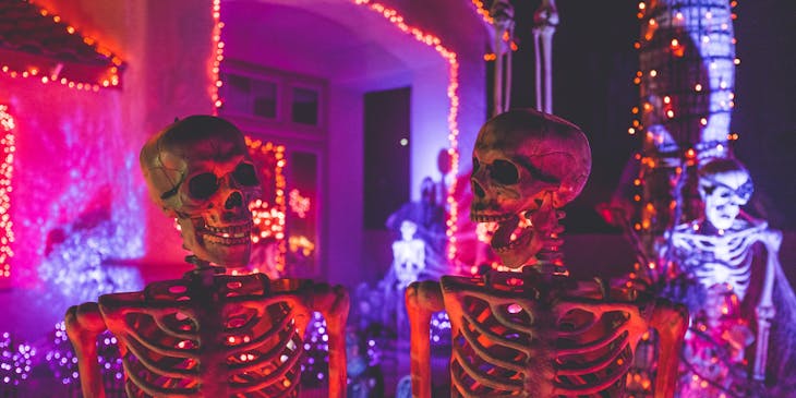 Dos calaveras mirándose entre sí en una casa embrujada decorada con luces