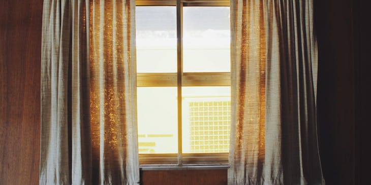 Cortinas suspendidas por una varilla que enmarca una ventana en un negocio de cortinas.