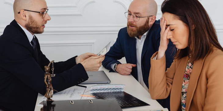 Un abogado hablando con dos clientes en un negocio de liquidación de empresas.