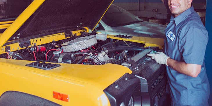 Un mecánico abriendo el capó de un automóvil en un taller móvil.