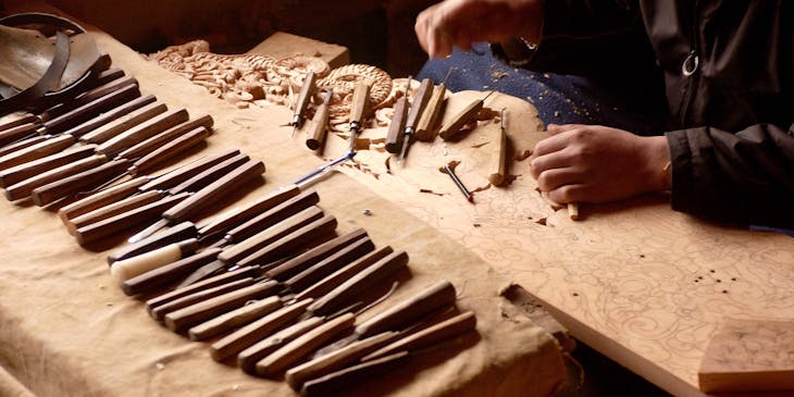 Un artesano creando una escultura decorativa en un negocio de artesanías en madera.