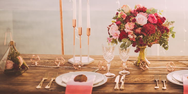 Una mesa de banquete decorada con flores y vajilla blanca con dorado en un negocio de planificación de bodas.