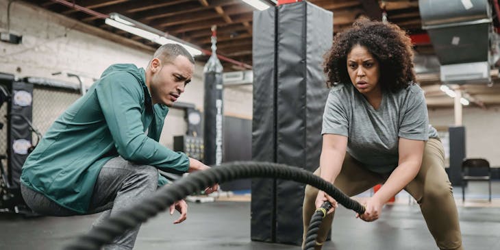 A health coach working with a client at the gym.