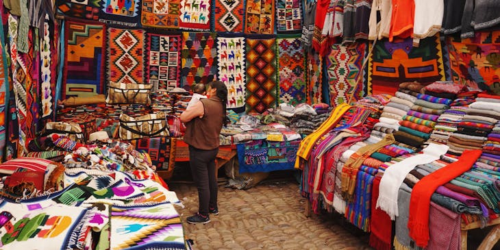 Una mujer cargando a un bebé en una tienda con mucho surtido de una empresa de alpaca.