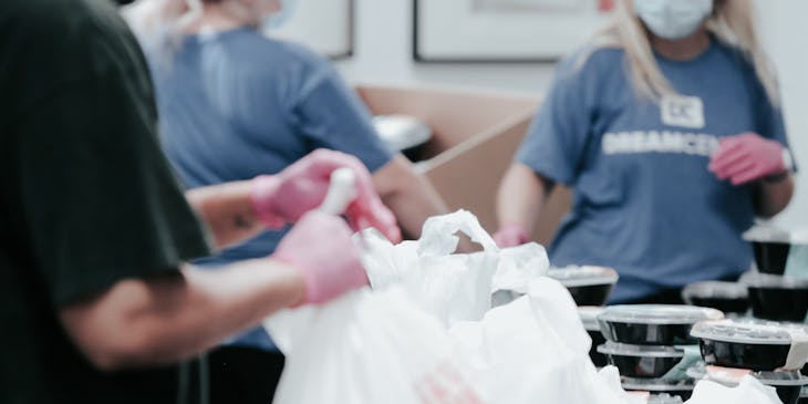 Personas organizando bolsas y charolas de alimentos en una institución de caridad.