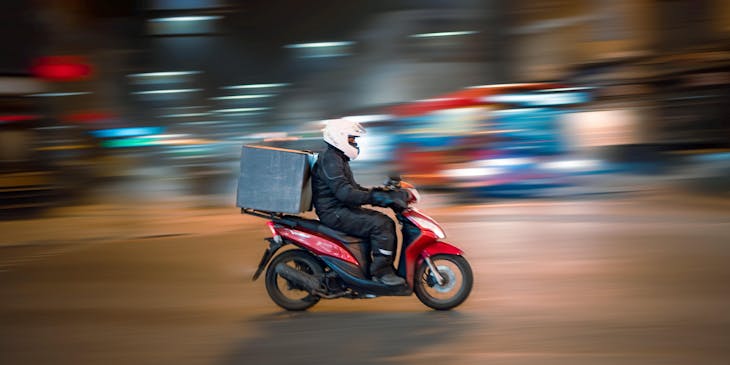 Persona en una moto trasladando un paquete en un negocio de mandados en moto.