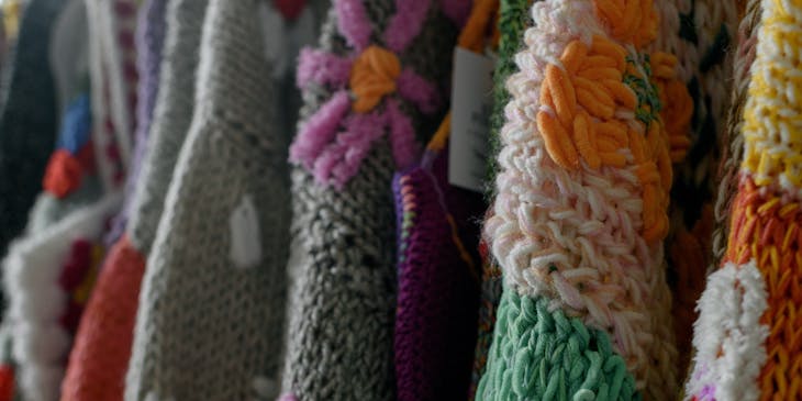 Suéteres con motivos florales colgados en un negocio de accesorios de alpaca.