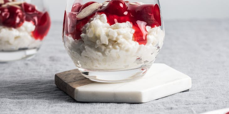 Arroz con leche servido con mermelada de cereza en un vaso de vidrio en un negocio de arroz con leche.