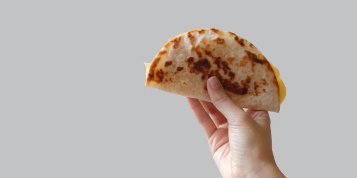 Una mano sosteniendo una baleada en un negocio de baleadas