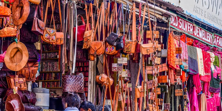 Negocio de carriel con carrieles exhibidos colgando del techo en un mercado turístico y dos personas viendo los productos