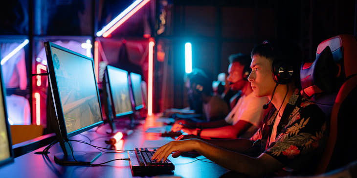 Grupo de jugadores sentados frente a su computadora en un negocio de deportes electrónicos.