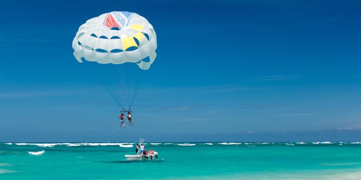 Una pareja en un parasailing sobre el mar siendo empujados por una lancha de un negocio de parasailing.