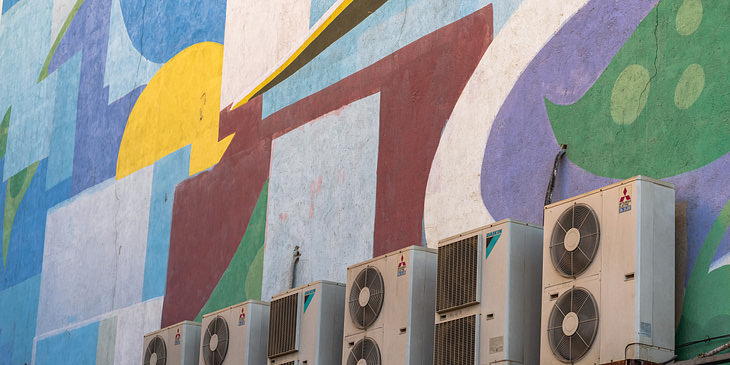 Equipos de refrigeración empotrados en el exterior en una pared decorada con pinturas abstractas de un negocio de refrigeración.