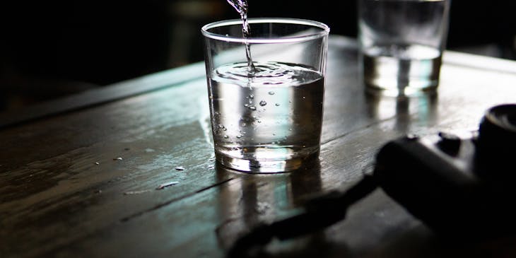 Una botella sirviendo su contenido en un vaso sobre una barra en un negocio de singani.