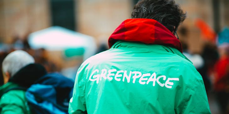 Activista de una organización ambiental vistiendo una chamarra de color verde con el nombre de Greenpeace.