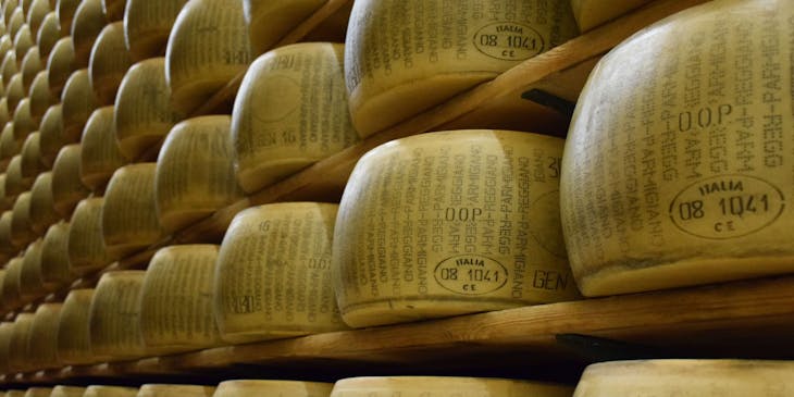 Uno scaffale pieno di forme di Parmigiano Reggiano in un caseificio.