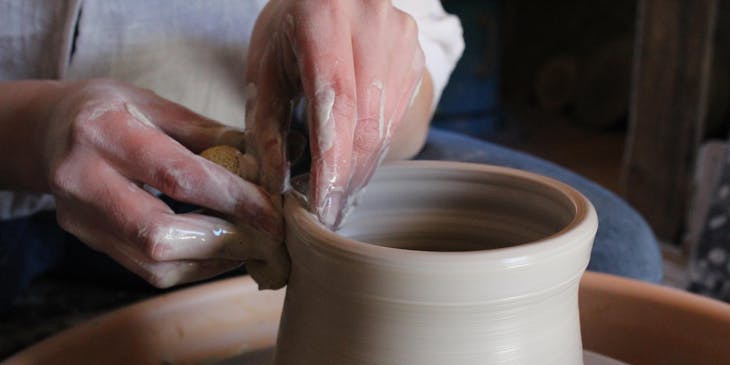 Un·e artisan·e train de faire un pot sur un tour de poterie.