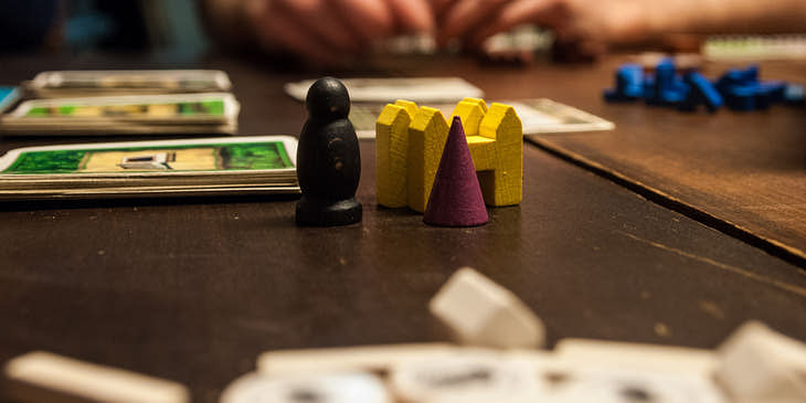 Des amis entrain de jouer une partie de colons de catan en cours dans un bar à jeux