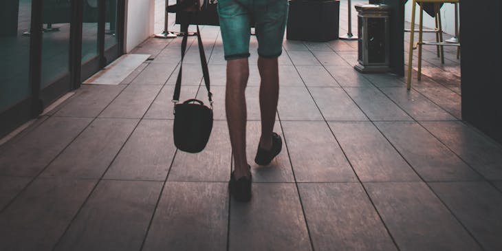 Un homme avec sa sacoche en train de marcher sur une terrace.