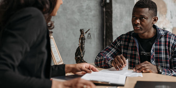 A young immigrant talking with his lawyer at an immigration law firm.