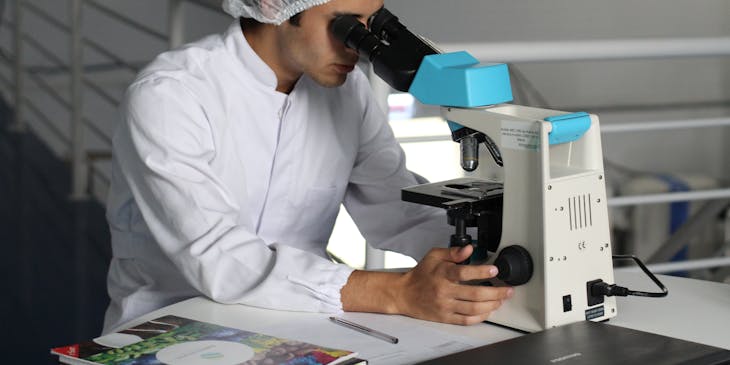 Un doctor mirando a través de un microscopio en un consultorio de alergología.