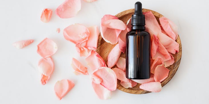 Aromatherapy oil diffuser beside pink and white carnations.