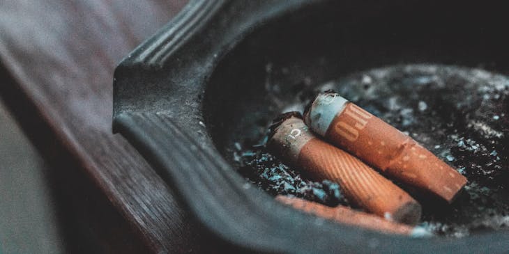 Colillas de cigarros en un cenicero color gris grafito sobre una mesa de caoba en un negocio de ceniceros.