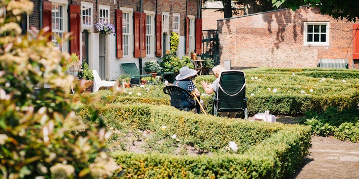 Two elderly ladies sitting in the gardens of an assisted living facility.