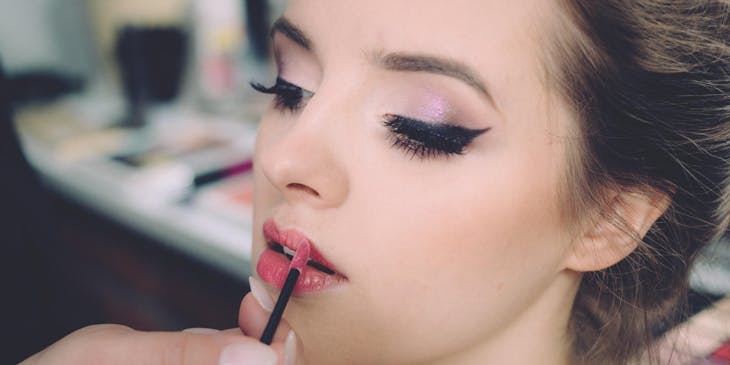 Una esteticista aplicando lápiz labial rojo a un cliente en un beauty parlour.