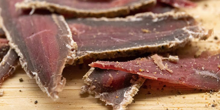 Rodajas de cecina sobre una tabla de cortar de madera en un negocio de beef jerky.