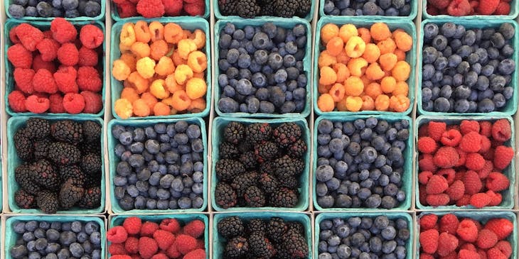 Bandejas com diferentes tipos de frutas vermelhas.