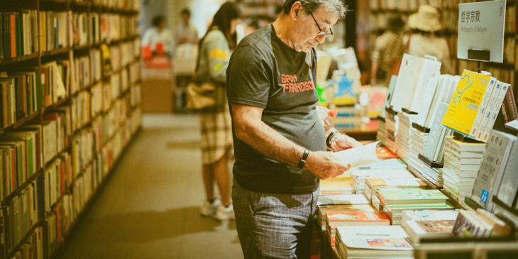 Un hombre leyendo un libro dentro de una librería.