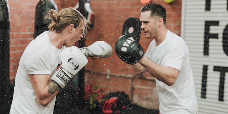 Dois homens lutando em uma academia de boxe.