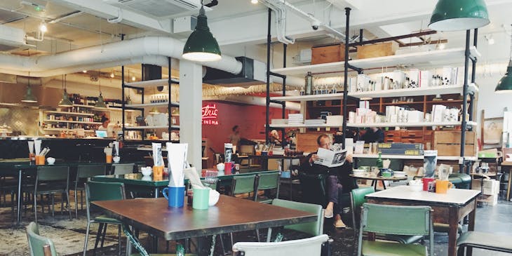 A cafeteria with white and green chairs and wooden tables.