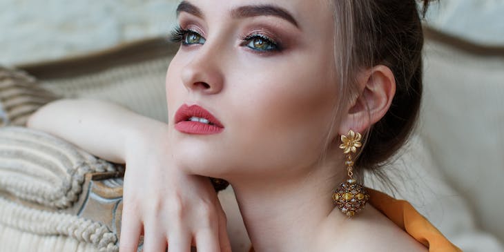 Une femme captivante aux lèvres roses et aux boucles d'oreilles en or.