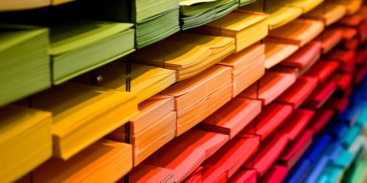 Piles of neatly-stacked, colorful folders at a cards & stationery business.