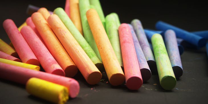 Una variedad de tizas en diferentes colores sobre una superficie negra con un fondo negro en el aparador de una empresa productora de tiza.