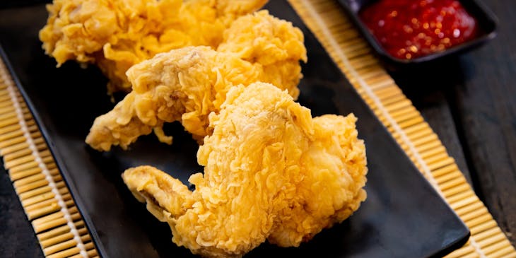 Trois ailes de poulet frites sur un plat noir dans un restaurant de chicken wings.