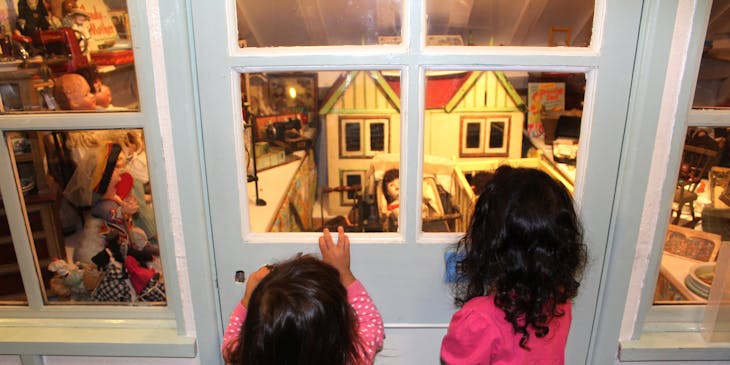 Dos niñas mirando una exhibición de casa de muñecas en un museo para niños