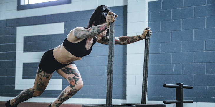 Une femme poussant l'équipement de l'entreprise CrossFit