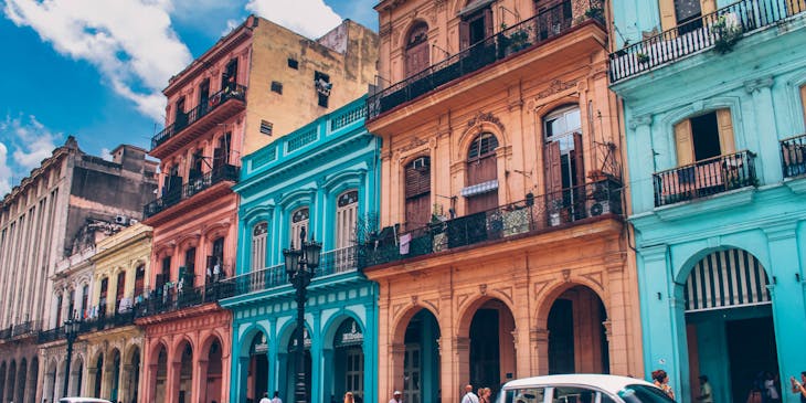 Un automóvil en una calle en Cuba cerca de un negocio con nombre cubano.