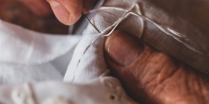 Une personne fait des points de broderie avec une aiguille à broder.