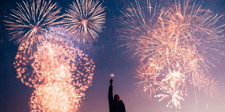 Un hombre que sostiene una bengala frente a fuegos artificiales en un negocio con nombre explosivo.