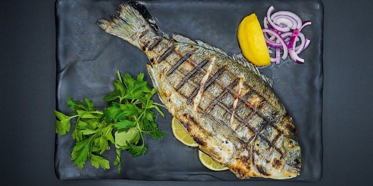 A grilled fish served on a plate in a fish restaurant.