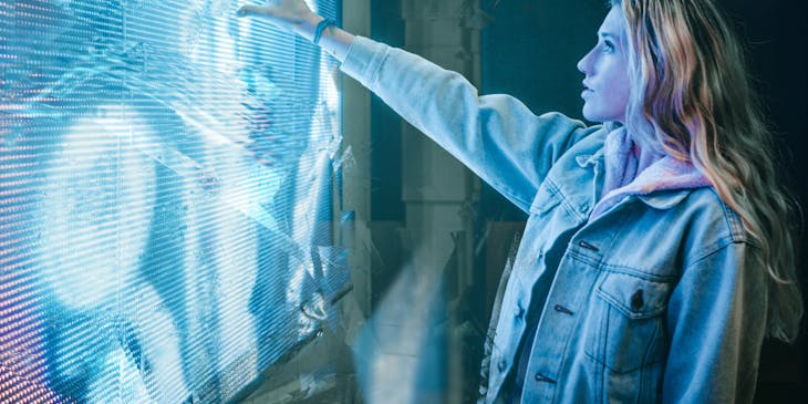 A woman touching a futuristic-looking light panel.