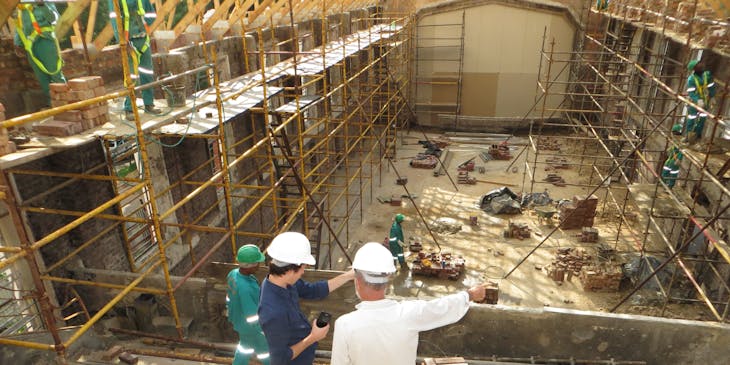 Dos contratistas platicando en medio de una construcción de alto riesgo.